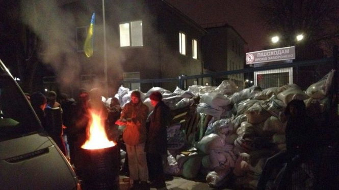 Люди в камуфляжной форме, которые заблокировали телеканал NewsOne в Киеве 3 декабря, начали обустраиваться у входов в канал, жгут костры и не планируют расходиться. 